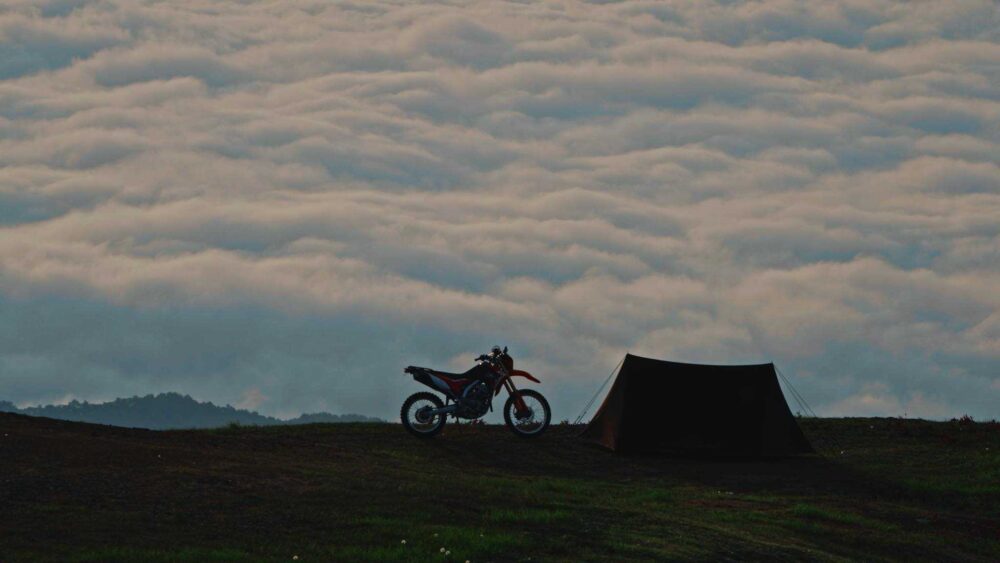 御嶽山の雲海を背景にしたバイクとテントのシルエット。静かな朝のキャンプ風景