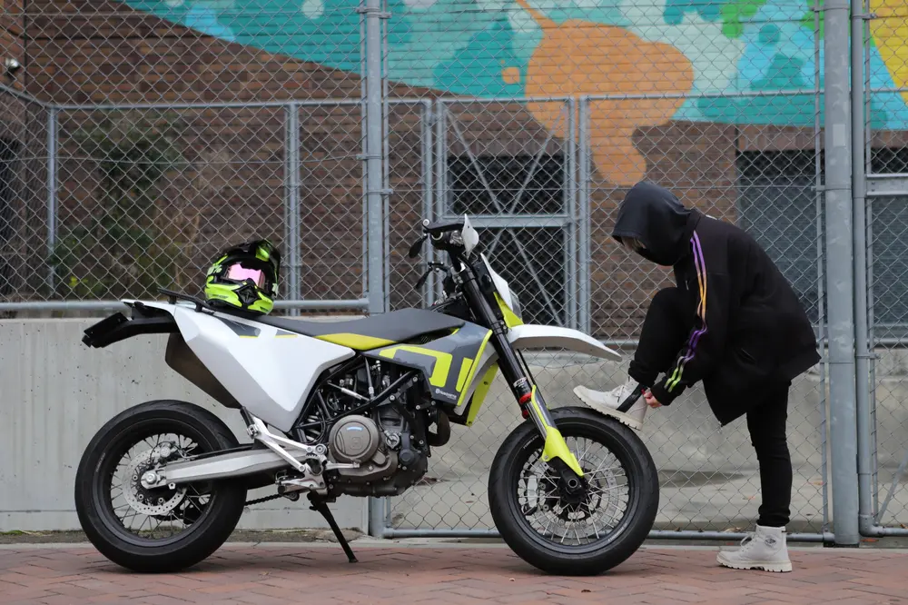 バイクの前で防水シューズの紐を締めるライダー。パラディウムの機能性とストリート感が伝わるカット。